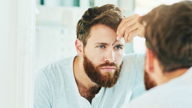 Mann zupft sich die Augenbrauen