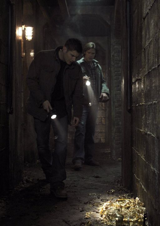 Als Sam (Jared Padalecki, r.) und Dean (Jensen Ackles, l.) auf eine Ansammlung von Goldstücken treffen, ist ihnen klar, dass der Feind nicht mehr w... - Bildquelle: Warner Bros. Television