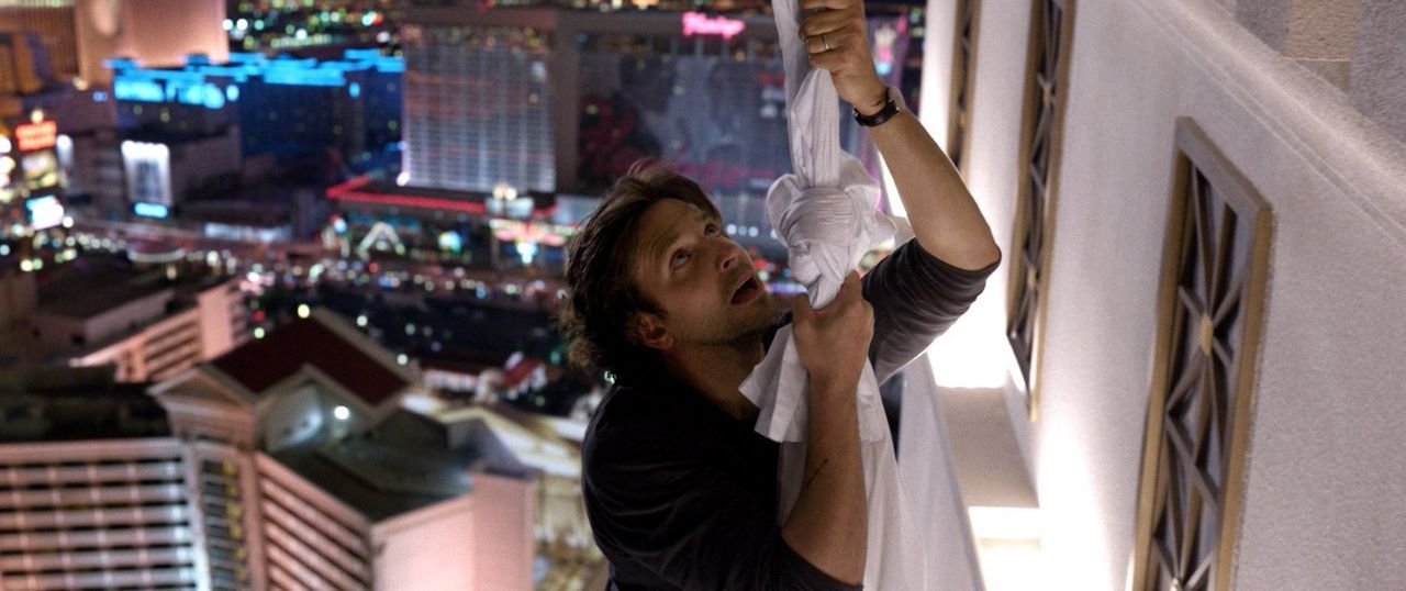 Jetzt hilft nur noch beten! Phil (Bradley Cooper) versucht sich mit Hilfe von Handtüchern abzuseilen, während Alan ihn absichern soll. Kann das gutg... - Bildquelle: 2013 Warner Brothers
