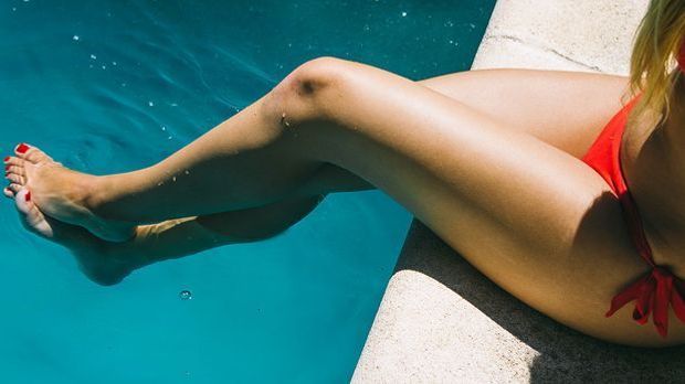 Gebräunte Beine im Sommer am Pool