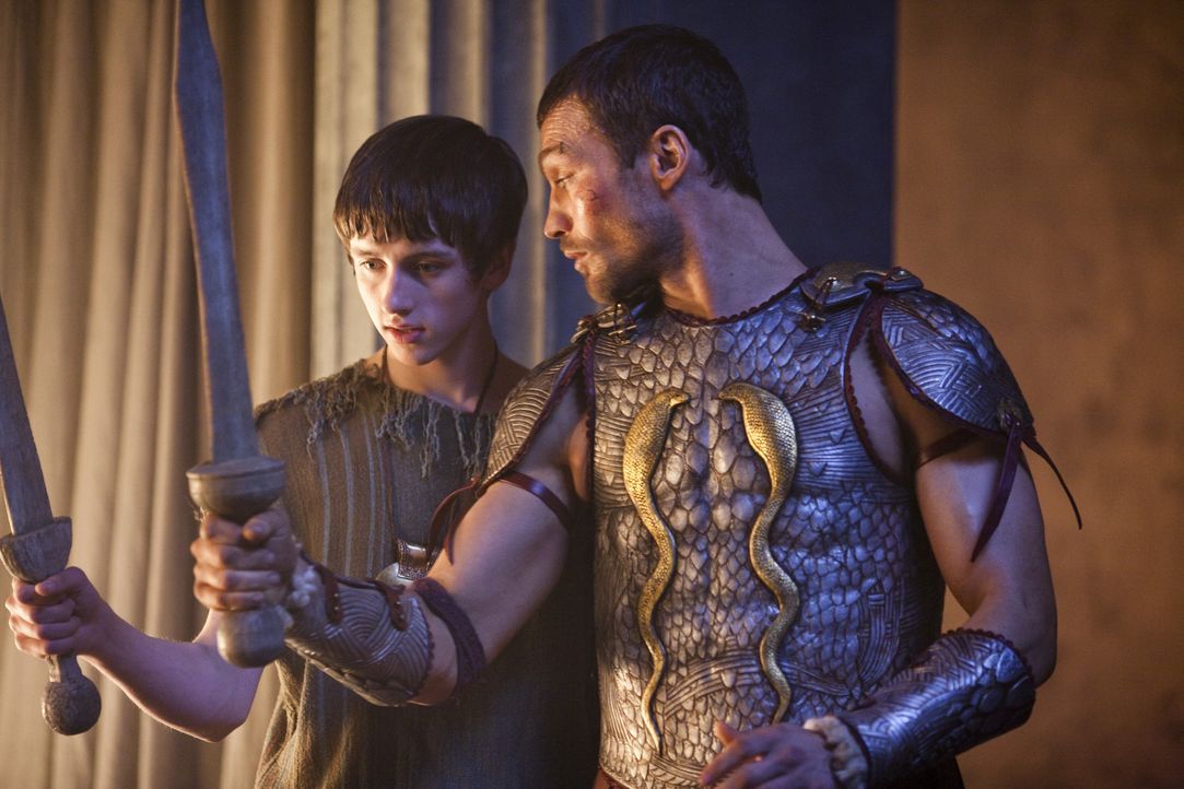 Magistrat Clavius besucht mit seinem Sohn Numerius (Lliam Powell, l.) die Gladiatorenschule, da Spartakus (Andy Whitfield, r.) dem Jungen Unterricht... - Bildquelle: 2010 Starz Entertainment, LLC