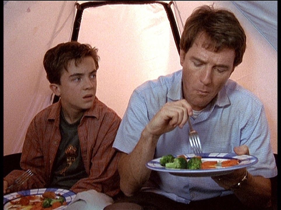 Hal (Bryan Cranston, r.) und Malcolm (Frankie Muniz, l.) haben sich in ein Zelt zurückgezogen, um wenigstens beim Essen nicht von Fledermäusen bel... - Bildquelle: TM +   2000 Twentieth Century Fox Film Corporation. All Rights Reserved.