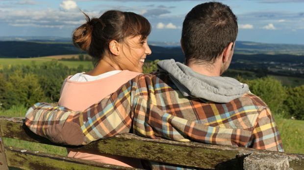 Un uomo e una donna seduti su una panchina.  Lui la cinse con un braccio...